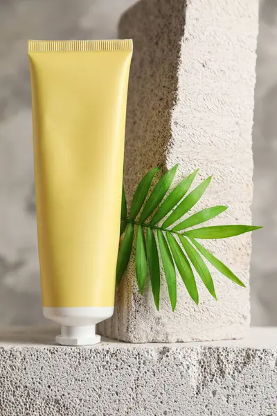 Beton blokta bir tüp krema ve yeşil yaprak