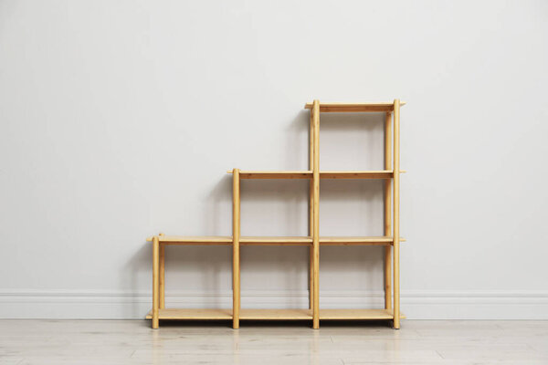 Empty wooden shelving unit near light grey wall indoors