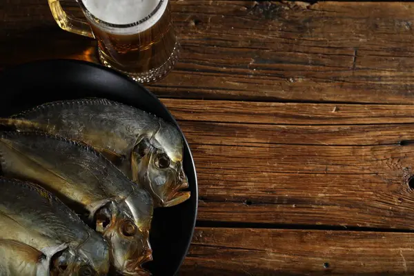 Kurutulmuş ay balığı ve bir bardak bira. Tahta masada, düz yerde. Metin için boşluk