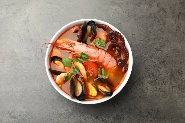 Lezzetli deniz ürünleri çorbası, gri dokulu masa, üst manzara.
