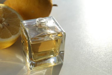 Aromatik yağlı parfüm şişesi ve parlak arka planda limonlar, yakın plan. Metin için boşluk