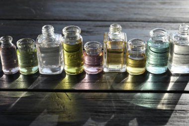 Siyah ahşap arka planda aromatik yağlı parfüm şişeleri, yakın plan.