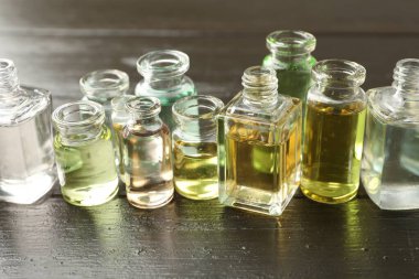 Siyah ahşap arka planda aromatik yağlı parfüm şişeleri, yakın plan.