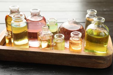 Siyah ahşap arka planda aromatik yağlı parfüm şişeleri, yakın plan.