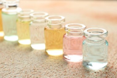 Bej desenli arka planda aromatik yağlı parfüm şişeleri, yakın plan.