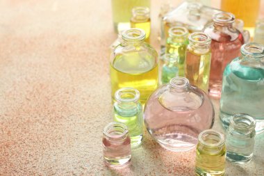 Bej desenli arka planda aromatik yağlı parfüm şişeleri, yakın plan. Metin için boşluk