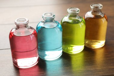 Ahşap arka planda aromatik yağlı parfüm şişeleri, yakın plan.