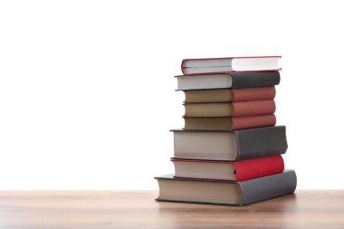 Beyaz arkaplana karşı ahşap masadaki eski kitaplar yığını