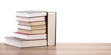 Beyaz arkaplana karşı ahşap masadaki eski kitaplar yığını