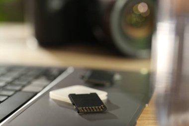 SD hafıza kartları, tutucu, dizüstü bilgisayar ve fotoğraf makinesi masada.