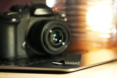 SD hafıza kartları, dizüstü bilgisayar ve fotoğraf makinesi masada, yakın plan.
