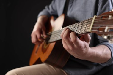 Siyah arka planda gitar çalan adam, ele odaklan.