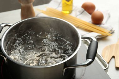 Tencereyi kaynar suyla pişirmek ve soba beyaz masada, yakın çekim.