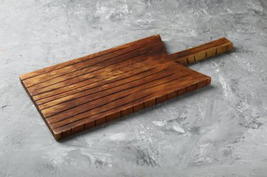 Açık gri desenli bir masada ahşap servis tahtası, yakın plan. Metin için boşluk