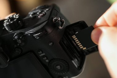 Bir adam fotoğraf makinesine SD bellek kartı yerleştiriyor.