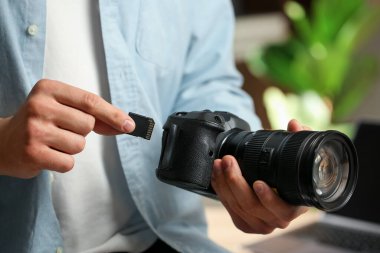Bir adam fotoğraf makinesine SD bellek kartı yerleştiriyor.