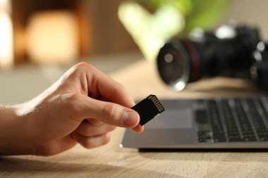 SD hafıza kartı olan bir adam ahşap masada, yakın plan.