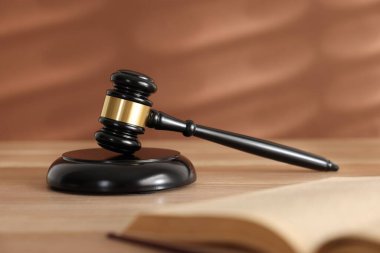 Hakimin tokmağı, ses bloğu ve tahta masa üzerindeki kitap mercan arka planına karşı, seçici odaklanma