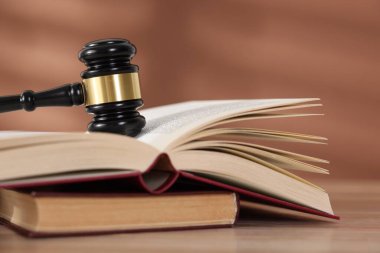 Hakimin tokmağı ve kitapları ahşap masada, kahverengi arka planda, yakın plan.