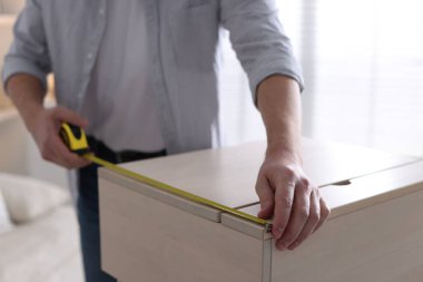 İçerideki bantla ahşap dolabı ölçen adam, yakın plan.