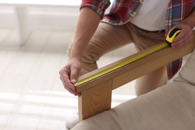 Koltuğunu bantla ölçen adam, yakın plan.