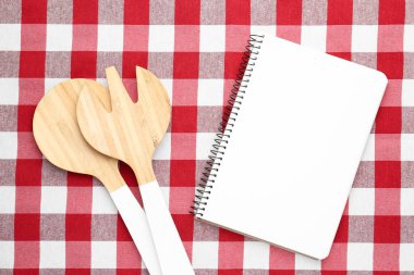 Kareli masa örtüsü üzerinde boş tarif kitabı ve mutfak gereçleri, düz konum