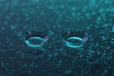 Bir çift kontakt lens ve su damlası aynanın yüzeyine düşer. Yakın plan.