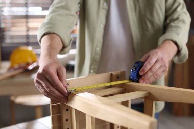 İçerideki bantla ahşap tabureyi ölçen adam, yakın plan.