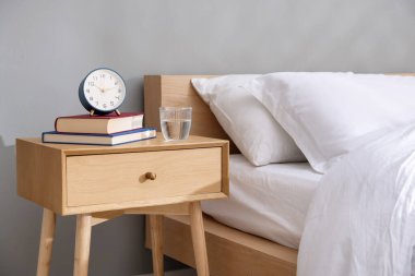 Yatağın yanındaki yatağın yanında kitaplar, çalar saat ve bir bardak su vardı.