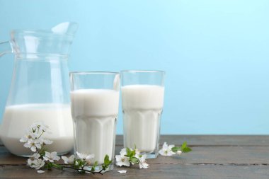 Taze süt ve çiçekler beyaz masada açık mavi arka planda. Metin için boşluk