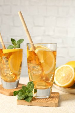 Buzlu çayı pipetle tazelemek, nane ve limon yeşil arka planda hafif desenli masada, yakın plan