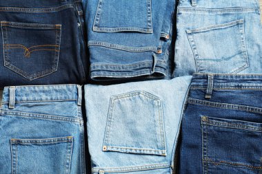 Different stylish jeans as background, top view