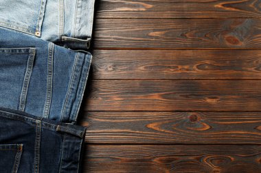 Different stylish jeans on wooden background, flat lay. Space for text