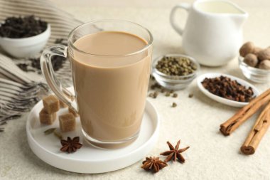 Cam bardakta Aromatik Masala çayı, beyaz desenli masada baharatlar ve kahverengi şeker, yakın plan.