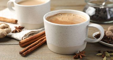 Ahşap masada fincanlarda ve baharatlarda Aromatik Masala çayı, yakın plan