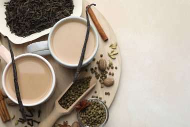 Açık gri masada fincanlarda, baharatlarda ve kuru yapraklarda Aromatik Masala çayı, üst manzara. Metin için boşluk