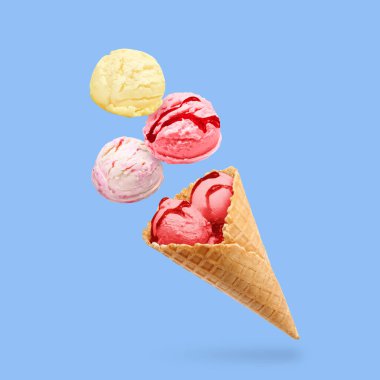 Dondurma kepçeleri ve waffle külahı mavi arka planda havada