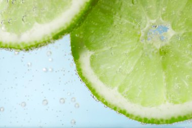 Açık mavi arka planda limon dilimli soda, yakın plan.