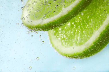 Açık mavi arka planda limon dilimli soda, yakın plan.