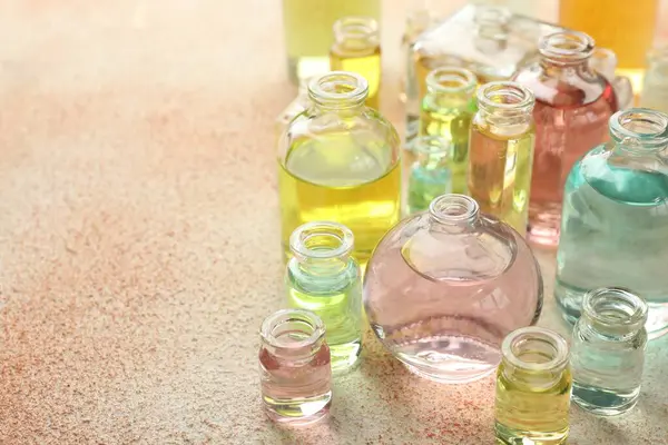 Bej desenli arka planda aromatik yağlı parfüm şişeleri, yakın plan. Metin için boşluk