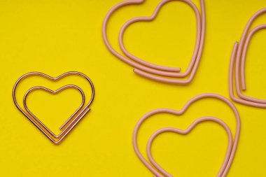 Sarı zemin üzerinde kalp şeklinde ataçlar, düz uzanmış.