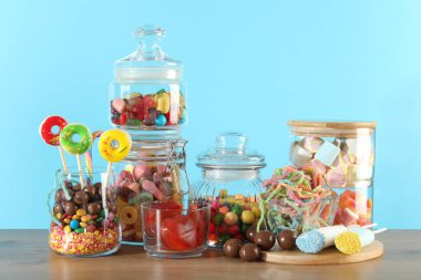 Çikolata. Açık mavi arkaplana karşı ahşap masada bir sürü farklı tatlı