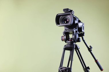Hafif zeytin zemininde tripodu olan modern video kamera, metin için boşluk