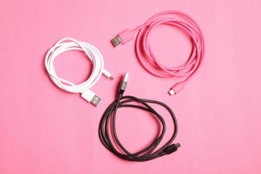 Pembe arkaplandaki USB şarj kabloları düz yatıyordu