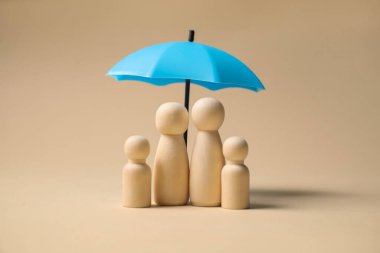 Bej arka planda şemsiye altında insan figürleri. Sigorta konsepti