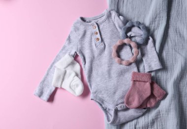 Pembe arka planda bebek kıyafetleri, battaniye ve ipler düz yatıyordu.