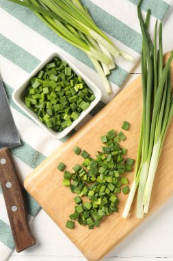 Taze yeşil soğan ve bıçak beyaz ahşap masada, düz yatıyordu.