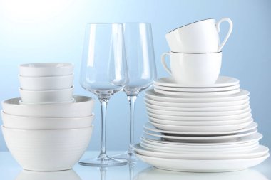 Different clean dishware on light blue background