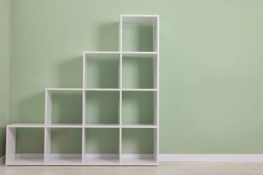 Empty shelving unit near olive wall indoors