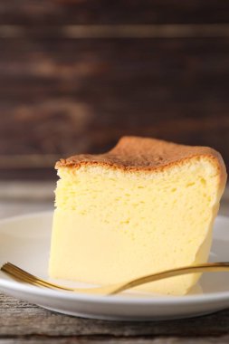 Piece of tasty Japanese Castella sponge cake and fork on table, closeup